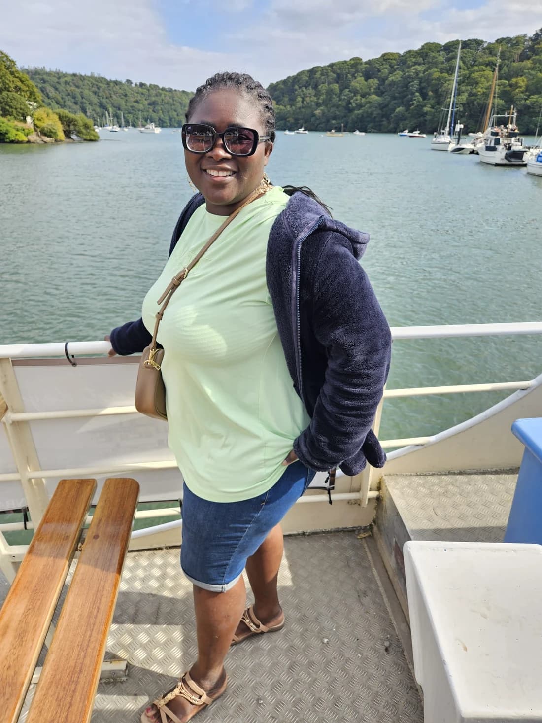 Karen smiling on a boat beside the water
